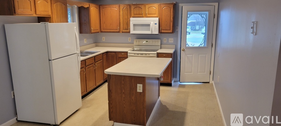 A kitchen with white appliances and wooden cabinets.
