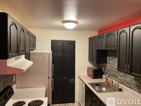 A kitchen with black cabinets and a white stove top oven.