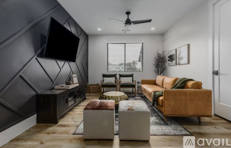 A modern living room with a dark grey accent wall and a large flat screen TV mounted on it.