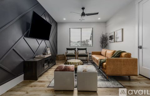 A modern living room with a dark grey accent wall and a large flat screen TV mounted on it.