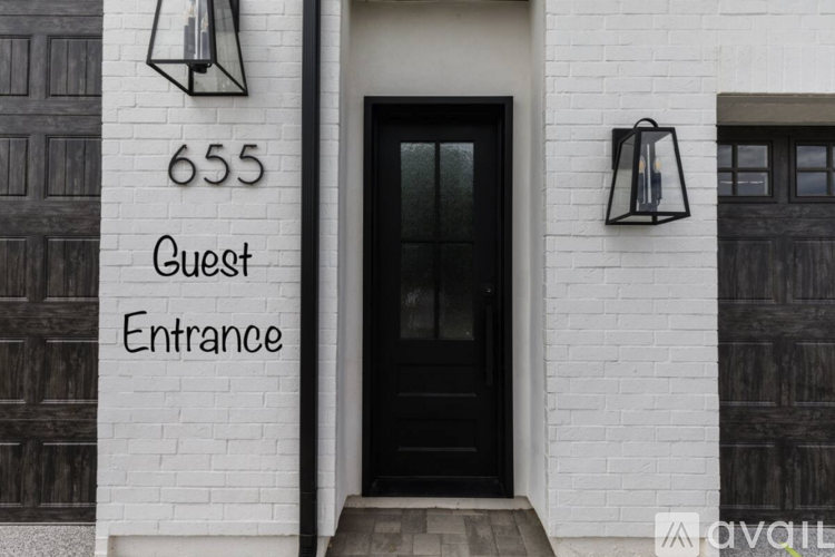 A black door with a glass window and a sign that says Guest Entrance.