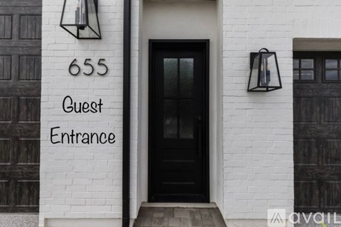 A black door with a glass window and a sign that says Guest Entrance.