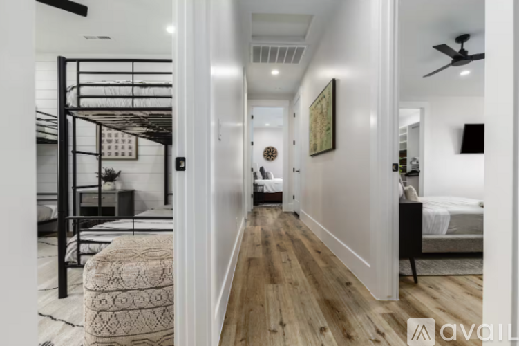 A hallway with a bedroom at the end and a bed with a white comforter.