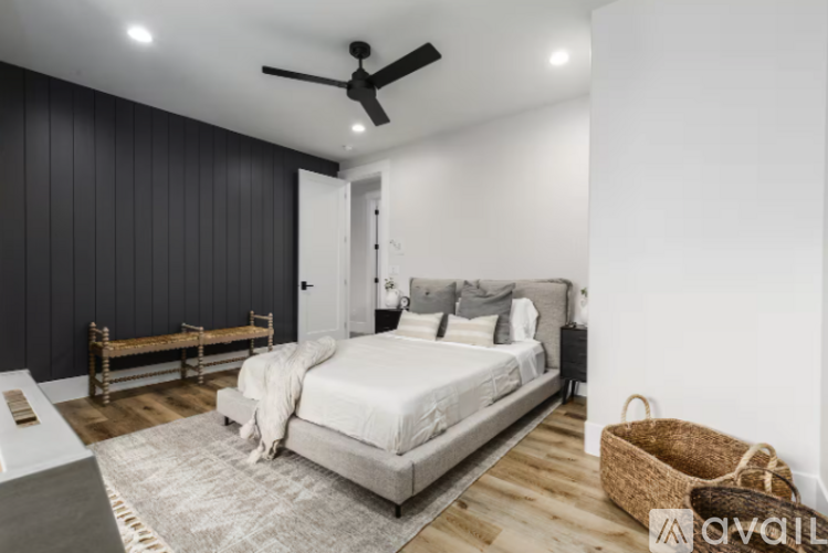 A bedroom with a bed, a bench, and a ceiling fan.