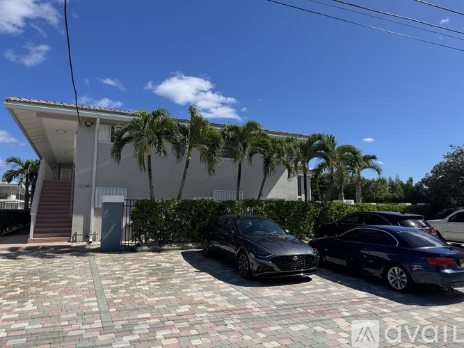 A white building with a palm tree in front of it.