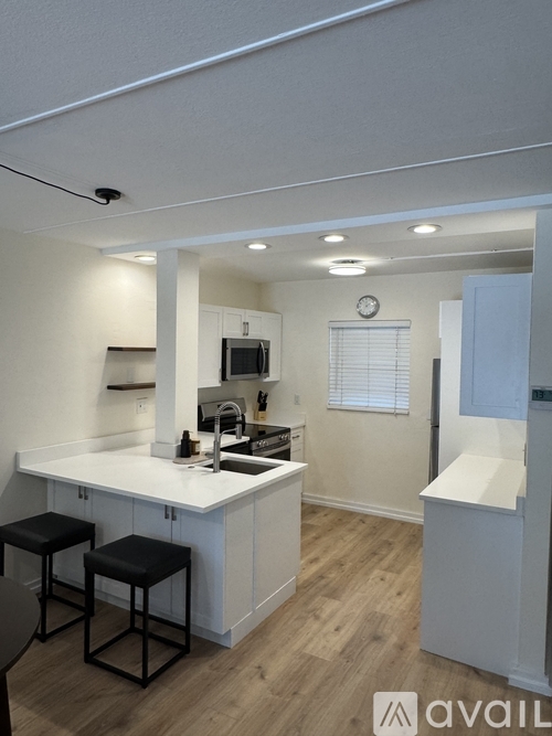 A kitchen with white cabinets and a black stool.