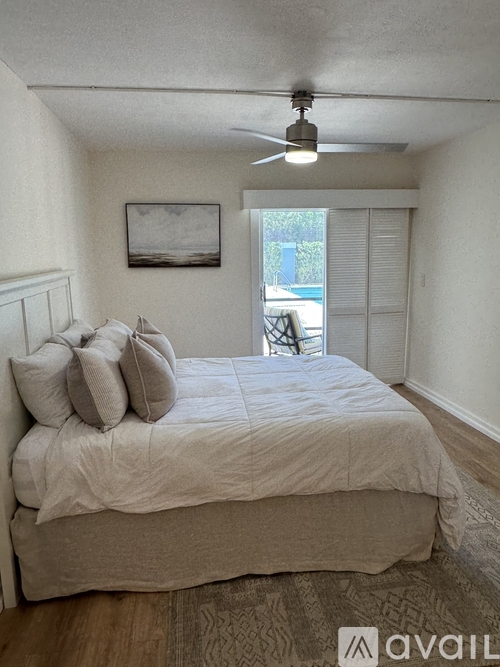 A bedroom with a bed, pillows, a ceiling fan, and a window with blinds.