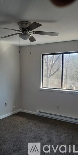 A room with a ceiling fan and a window.