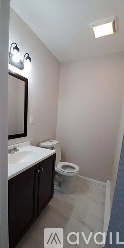 A bathroom with a toilet, sink, and mirror.