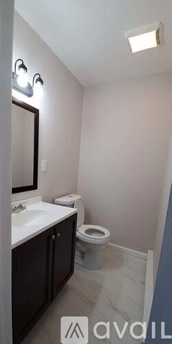 A bathroom with a toilet, sink, and mirror.