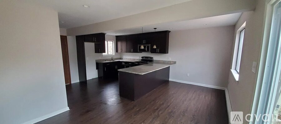 A kitchen with dark wood floors and a large island.