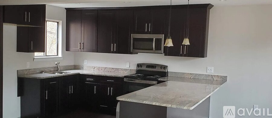 A kitchen with dark brown cabinets and a granite countertop.