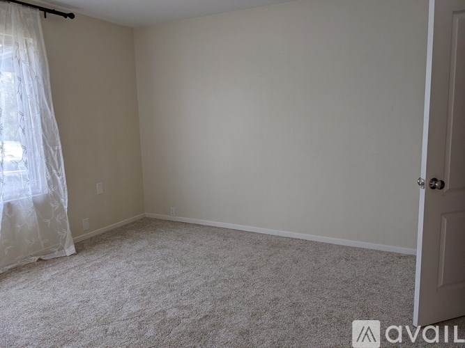 A room with a carpeted floor and a door on the right side.