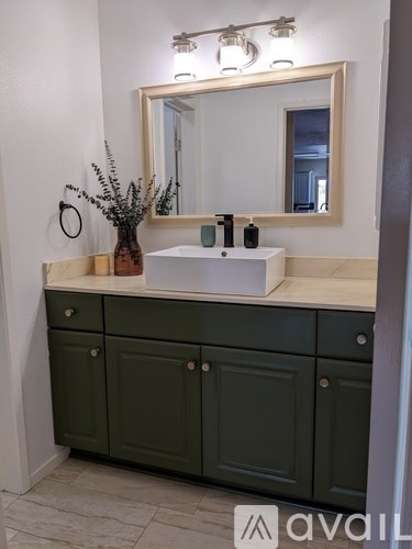 A bathroom vanity with a mirror and a green cabinet.