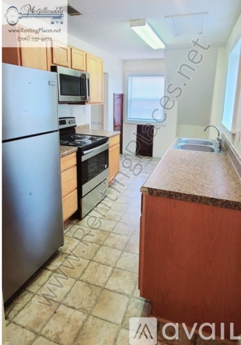 A kitchen with a refrigerator, oven, microwave, sink and cabinets.