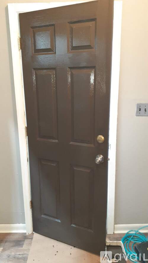 A brown door with a silver handle is in a room with white walls.