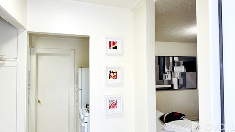 A white door is open to a hallway with pictures on the wall.