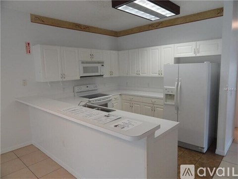 A kitchen with white cabinets and appliances is available for rent.