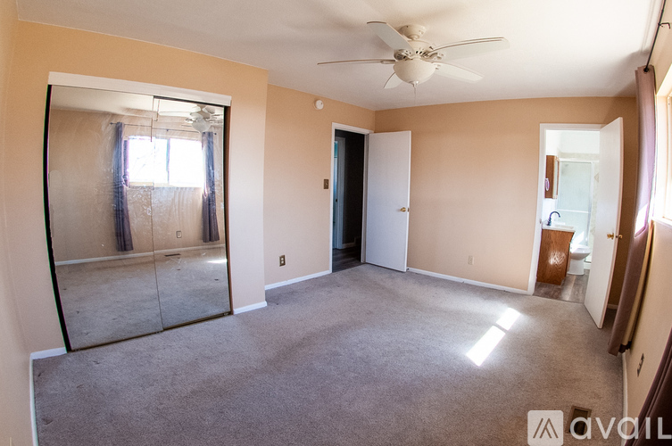 A spacious room with a ceiling fan and a large mirror on the wall.