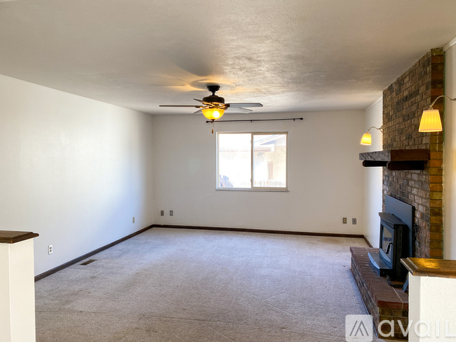 A living room with a fireplace and a ceiling fan.