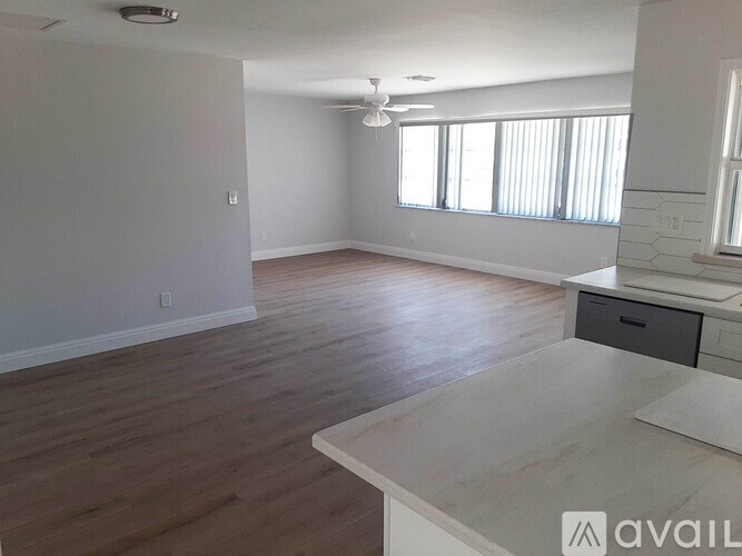 A spacious room with wooden flooring and a large window.