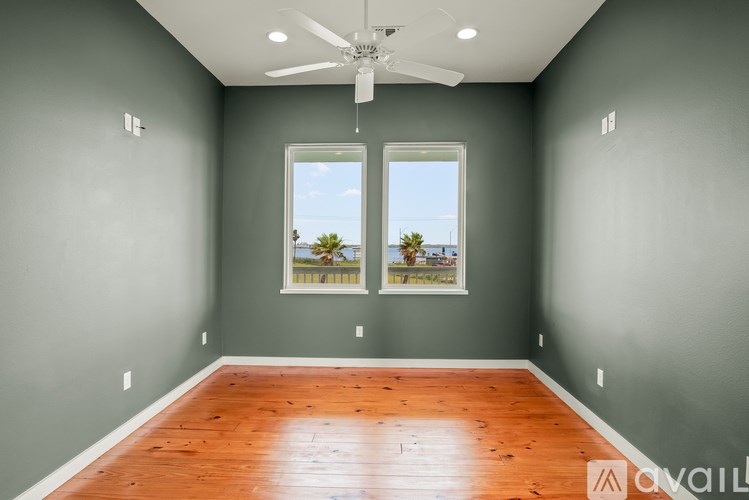 A room with a ceiling fan and two windows.