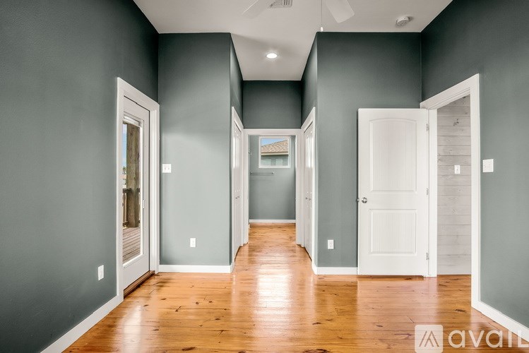 A long, narrow hallway with wooden floors and white doors on either side.