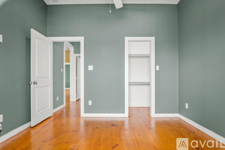 A room with a white door and a wooden floor.