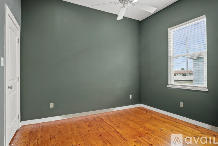 A room with a wooden floor and a window with blinds.