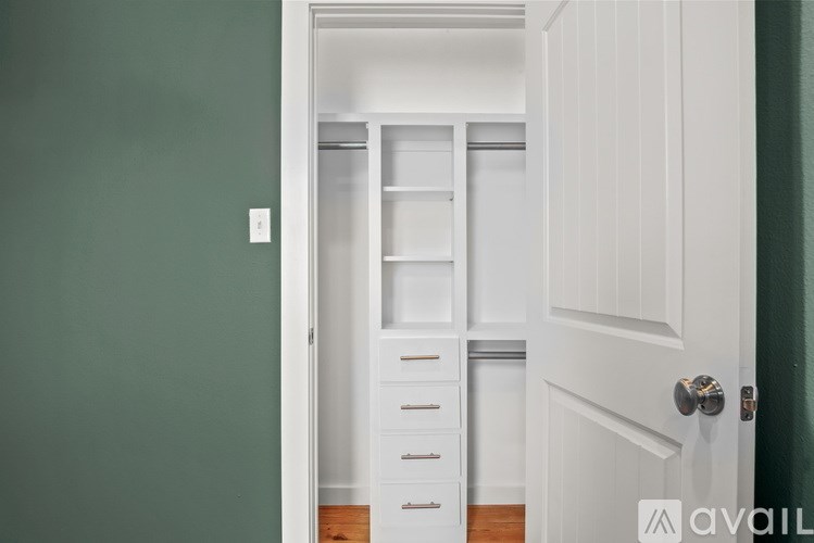 A white door with a silver handle and a white shelf unit with drawers is in the room.