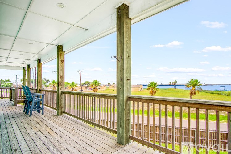 A wooden deck with a blue chair and a view of the ocean.