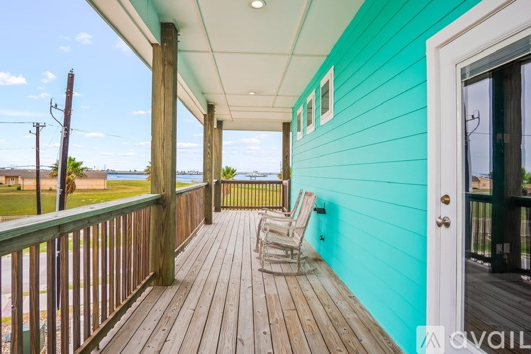 A blue house with a wooden deck and a white door.
