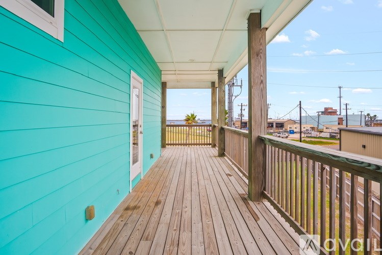 A wooden deck with a green wall and a white door.