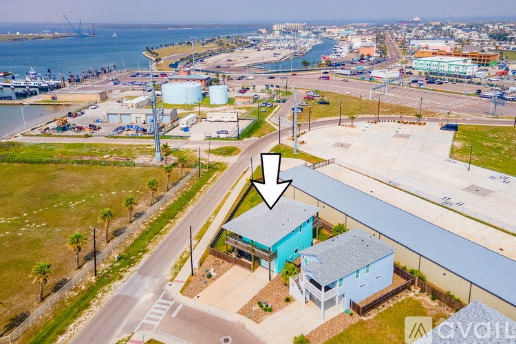 A bird's eye view of a street with a blue building and a white arrow pointing to it.