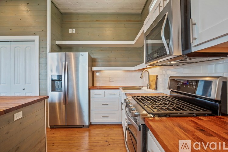 A kitchen with a wooden counter top and stainless steel appliances.