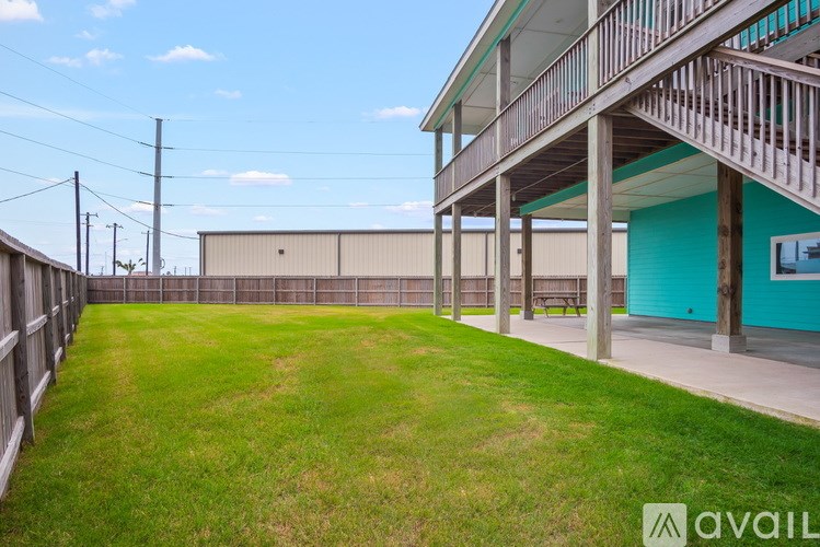 A large grassy area with a wooden fence and a building with a blue wall and a balcony.