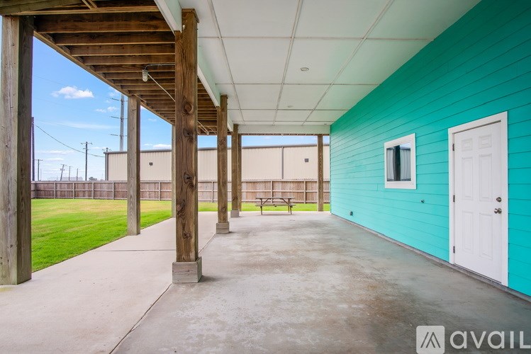 A blue building with a white door and a wooden pergola.