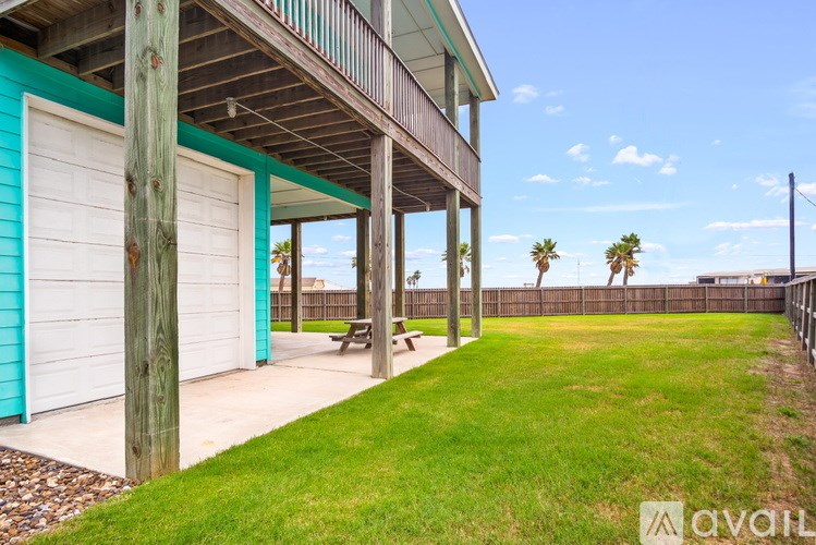 A wooden deck with a white garage door is surrounded by a grassy area.