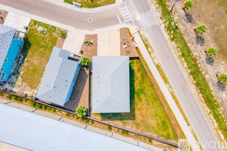 A bird's eye view of a road with a blue building on the left and a grey building on the right.