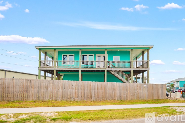 A two-story house with a green exterior and a wooden fence in front.