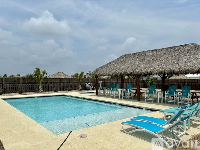A pool with blue water and a thatched roof.