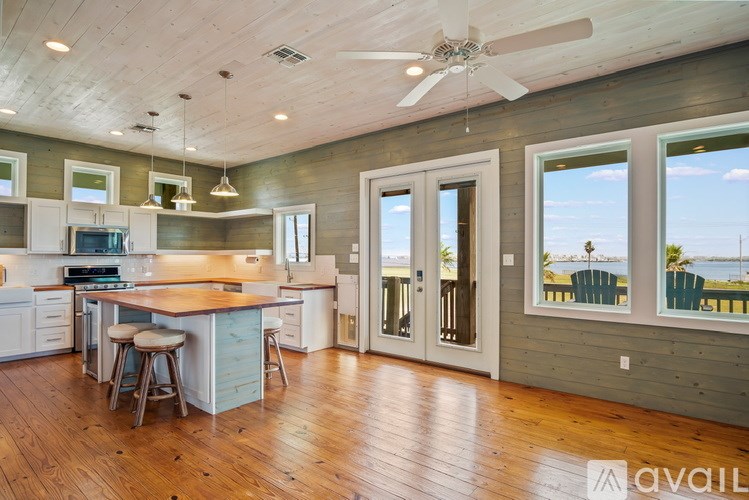 A spacious kitchen with wooden floors and a ceiling fan.