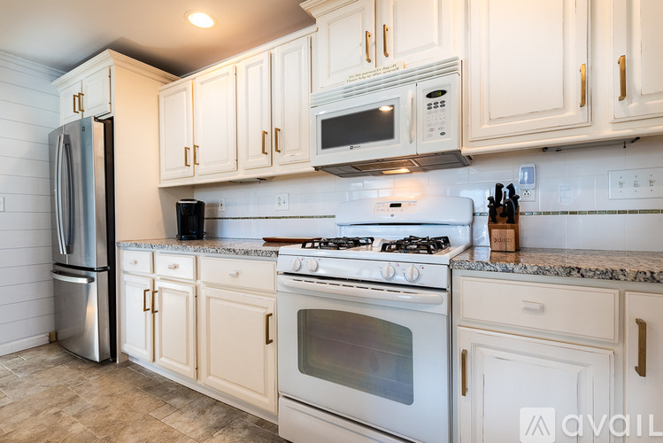 A kitchen with white cabinets and appliances.