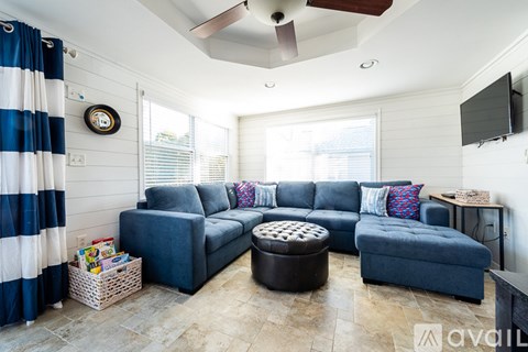 A living room with a blue couch and a fan on the ceiling.