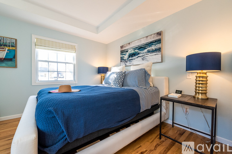 A bedroom with a bed, two lamps, and a painting on the wall.