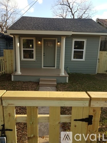 A small house with a front porch and a wooden fence.