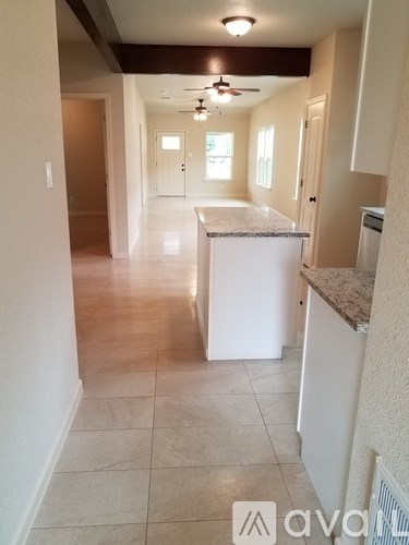 A kitchen with white cabinets and a marble countertop.
