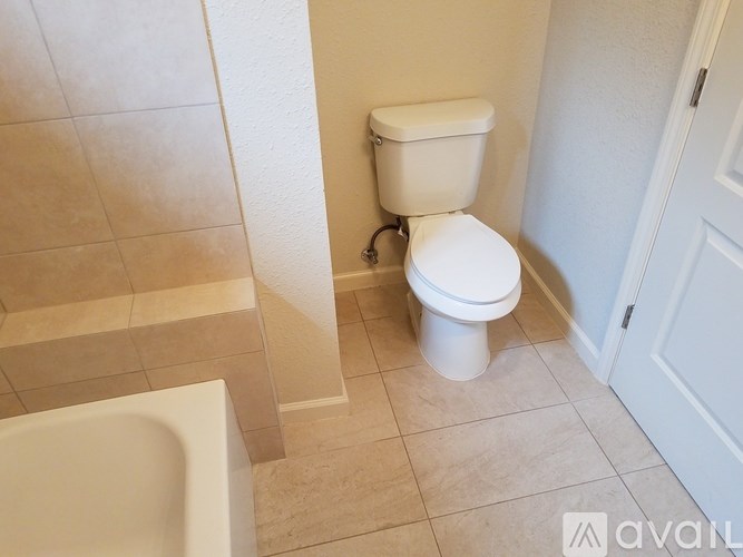 A white toilet in a bathroom with beige tiles.