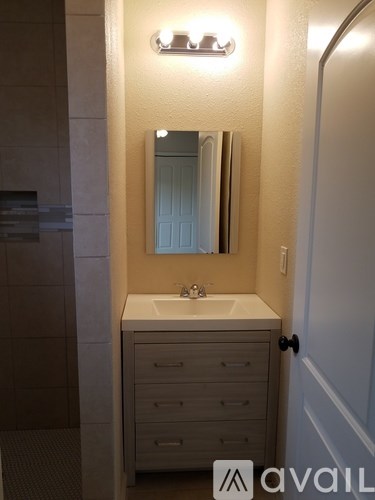 A bathroom with a sink, mirror, and cabinets.