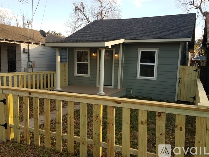 A small house with a porch and a fence.